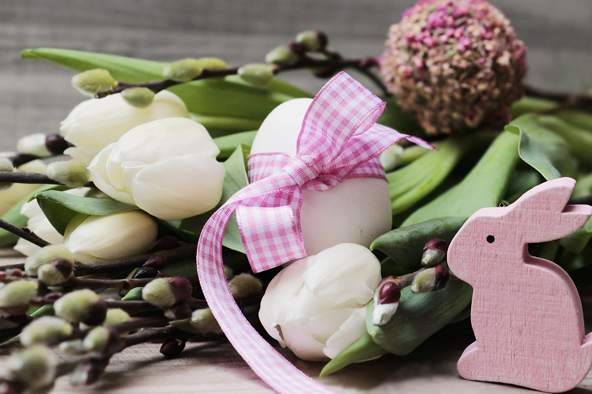 Osterdekoration mit Blumen, Eiern und einem Hasen aus Holz