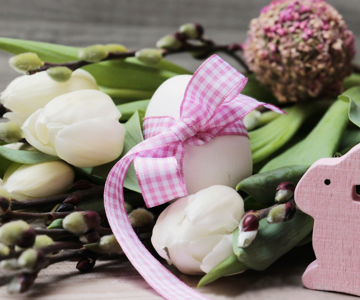 Osterdekoration mit Blumen, Eiern und einem Hasen aus Holz