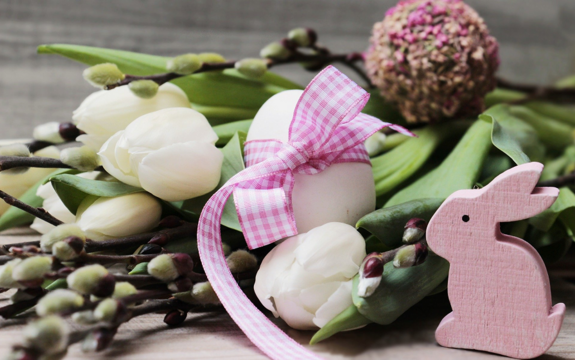 Osterdekoration mit Blumen, Eiern und einem Hasen aus Holz